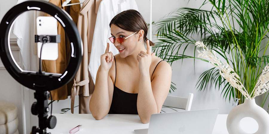 woman recording herself with a smartphone and a ring light while showing her sunglasses